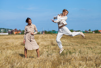 Two girls in a beige suit posing on a background of wheat in a cut field