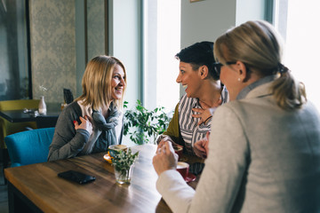 mid aged woman friends enjoying time drinking coffee in cafe