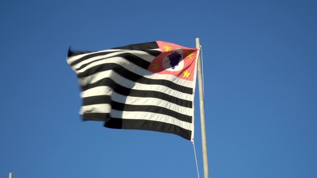 Beautiful flag of São Paulo state waving in the wind on sunny summer day with blue sky. Concept of state, symbol, republic, Brazil, cultural identity, democracy, geography and politics.