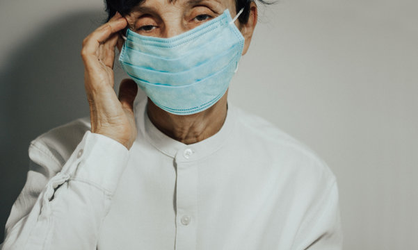Coronavirus quarantine and Air pollution pm2.5 concept. Sick sad depressed, thoughtful old woman wearing respirator mask for protect. Wuhan, China epidemic virus symptoms background.