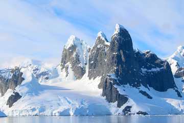 Snow-capped mountains and icy coasts at the entrance to the Lemaire Channel in the Antarctic Peninsula, Antarctica