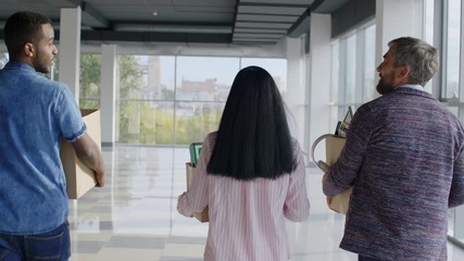 Rear view shot of colleagues with stuff entering new building and looking for their office