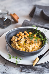 Chickpeas hummus in the black bowl decorated with sesame seeds and chickpeas greens. Vegan recipes, plant-based dishes. Green living concept. Organic food. Vegetarian