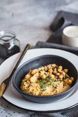 Chickpeas hummus in the black bowl decorated with sesame seeds and chickpeas greens. Vegan recipes, plant-based dishes. Green living concept. Organic food. Vegetarian