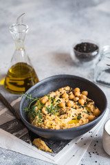 Chickpeas hummus in the black bowl decorated with sesame seeds and chickpeas greens. Vegan recipes, plant-based dishes. Green living concept. Organic food. Vegetarian
