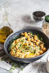 Chickpeas hummus in the black bowl decorated with sesame seeds and chickpeas greens. Vegan recipes, plant-based dishes. Green living concept. Organic food.