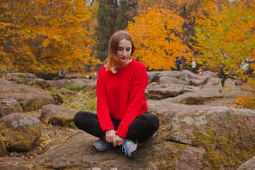 Naklejka na ściany i meble Young woman in the autumn forest. Traveler in a red sweater