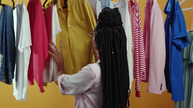 Happy african woman selecting stylish clothes on rack in retail shop. Portrait beautiful fashion designer girl standing near clothes hanger smile happy. Copy space.