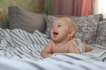 little chubby baby smiling while lying on the bed