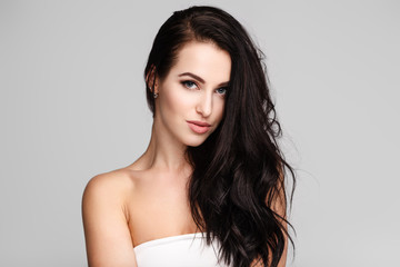 portrait of a young lady with beautiful brunette hair on grey