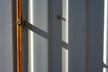Corrugated metal fence with rusty strip and bolts