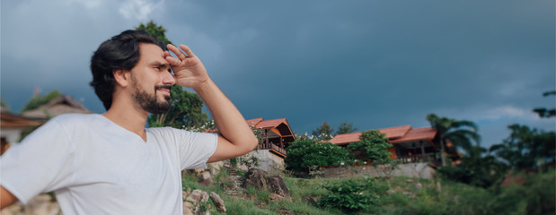 Portrait of a male tourist on the beach on the background of Thai national houses