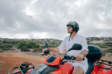 Naklejka premium A man sits on a quad in a helmet and glasses in the mountains
