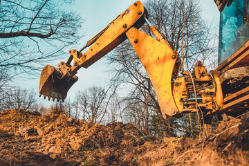 The excavator performs excavation work by digging the ground with a bucket in the forest.