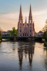 Fototapeta na wymiar View of St. Paul's church and Auvergne bridge from Royal bridge. Ill river. Early spring. Beautiful reflection. Strasbourg, Alsace, France