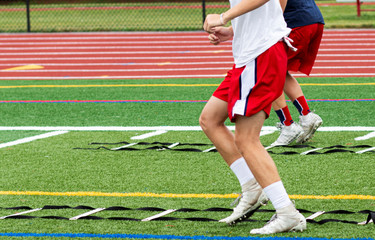 High school football players running ladder drills on the turf