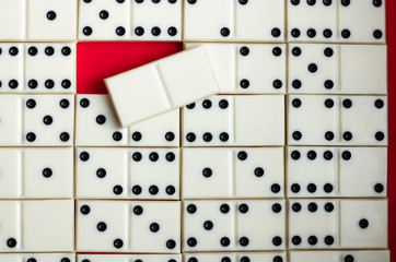 Dominoes Domino bones lie on a background of red fabric. Empty bone on top of others. Empty red cell. Background. View from above