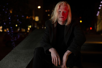 Albino man looking at the camera night city portrait