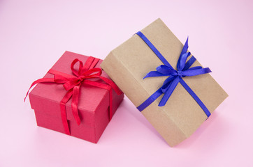 Gift with a blue and red ribbon on a pink background. Gift wrapping. Box with tape.