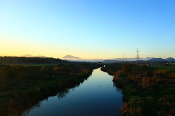 A Beautiful Twin Peak Mountain beyond a Quiet Stream at Sunset