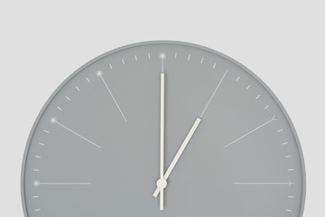Closeup of a grey wall clock isolated on light grey background. One o'clock. Time. Minimal styled.