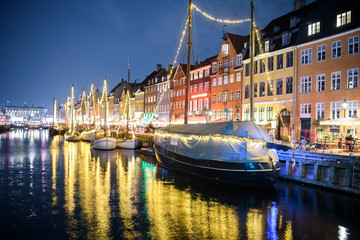 Fototapeta premium Evening view to boats in front of colourful old houses at Nyhavn harbour canal in Copenhagen, Denmark. February 2020