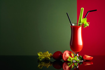 Tomato juice with celery on a black reflective background.