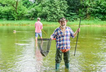 come to net. fishermen with fishing rods, selective focus. retired mature man fisher. hobby and sport activity. father and son fishing. male friendship. family bonding. summer weekend