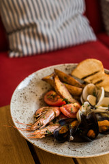 A plate with a variety of seafood stands on a table in a restaurant