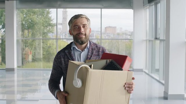 Portrait of smiling entrepreneur going through new office with stationery box