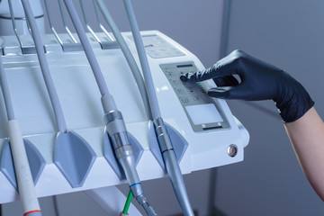 close-up, dentist doctor, in gloves, pressing a button on the device, to run programs on a medical dental device