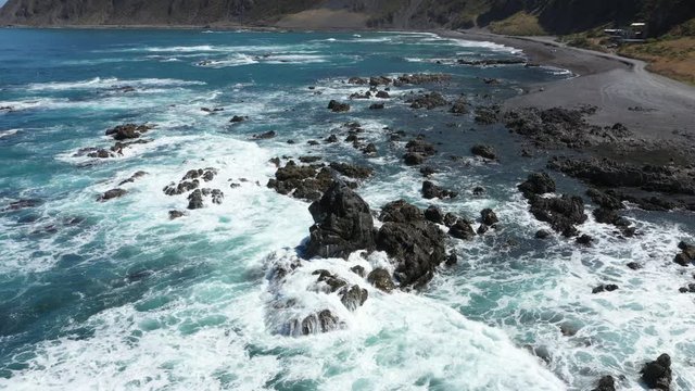 Aerial footage of rocks in black sand beach in Wellington, New Zealand