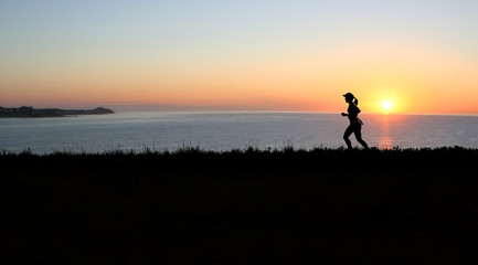 Woman jogger at sunset with ocean in the background