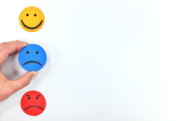 Happy, sad and angry face icons in white background. Hand choosing sadness. Customer satisfaction and negative service feedback concept.