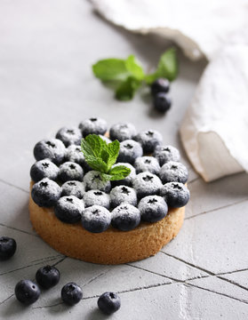 Dessert. Cake with blueberries and sugar powder on a light background. Background image, copy space