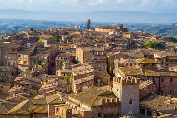 Fototapeta na wymiar Panoramic view of Siena from The Torre del Mangia. Medieval houses are located on the hillsides, tuscan hills on the horizon. Pictorial cityscape. Tuscany, Italy.