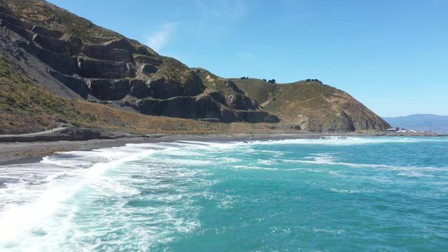 aerial footage of drone zooming in mountains over beach in Wellington, New Zealand