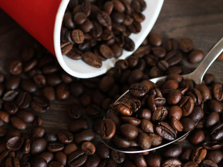 Coffee beans poured from a red plastic Cup