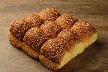 Brioches with sesame on the wooden table.