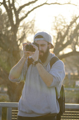 European man taking photos/ Bearded man wearing a gray hat taking photos/ photographer doing his job/ Young man with beard using a dslr camera