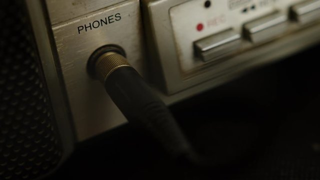 The old cassette player boombox headphone jack plugs into a headphone jack. Retro music concept.
