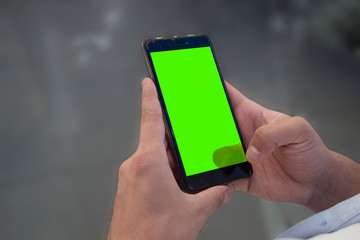 Mobile on hands with green screen.