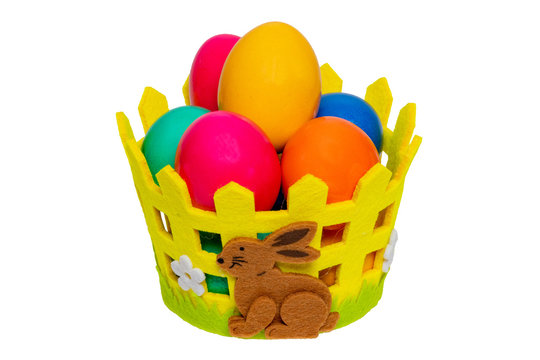 Easter decorations background. Close-up of colorful easter eggs in a basket with a brown bunny isolated on a white background. Decoration element for easter greeting card. Macro photograph.