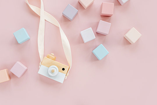 Wooden toy camera and colorful toy blocks. Stylish baby toys on pastel pink background. Eco friendly, plastic free toys accessories for kids. Flat lay, top view