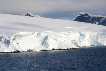 Fototapeta na wymiar The Antarctic polar pack. Snow-capped mountains and icy shores of the Antarctic Peninsula, Antarctica