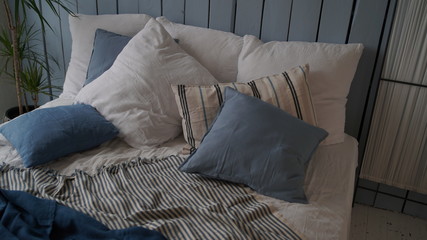Large bed with pillows and blankets. Wooden stand for breakfast on crumpled bed in studio. Close-up...
