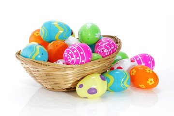 Fototapeta na wymiar Multi-colored toy easter eggs in a basket on white