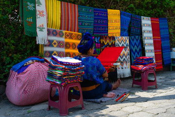 La mujer maya de Guatemala está tejiendo un rebozo de color rojo con un telar de cintura.