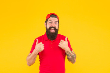 Naklejka premium Hiring shop worker. Hipster cashier. Delivery service. Restaurant cafe staff wanted. Man bearded tattooed hipster wear cap cashier uniform yellow background. Cashier concept. Salesman cashier career