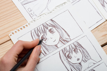 Artist drawing an anime comic book in a studio. - 327913774